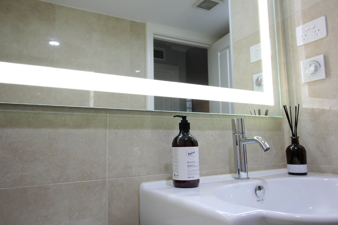 Bottom corner of a mirror with lights in a Sydney apartment